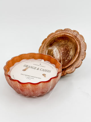Pumpkin wax candle with label "ORANGE & CASSIS" and scalloped lid