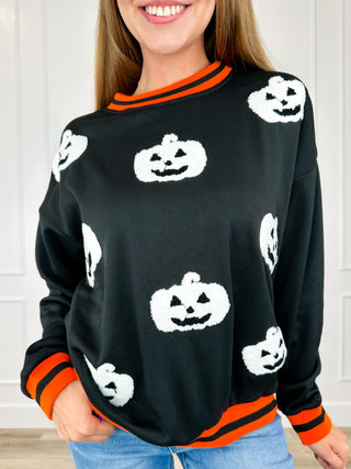 Black crewneck sweatshirt with long sleeves, white jack-o-lantern print and orange trim