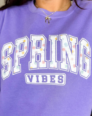 Purple sweatshirt with 'SPRING VIBES' text and floral designs on a plain background