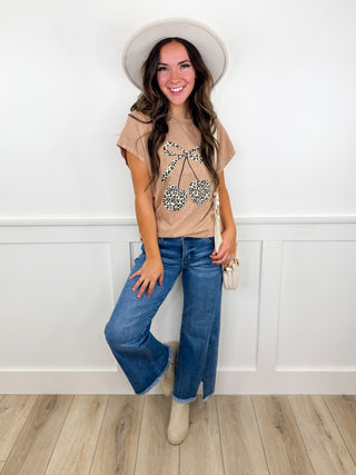 Women's outfit with tan embroidered top, blue wide-leg jeans, beige hat and boots