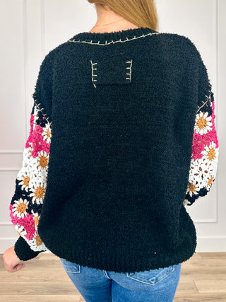 Back view: dark knit long-sleeve sweater top with floral sleeves and keyhole back detail