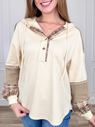 Cream cotton hooded long-sleeve top with plaid cuffs and half-button placket