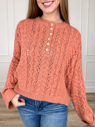 Orange cable-knit cropped sweater top with long sleeves and button placket