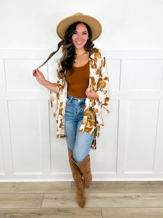 Women’s patterned kimono top with blue jeans and tan knee-high boots
