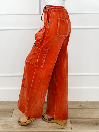 Rust orange wide-leg cargo pants with elastic waistband and flap patch pockets