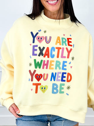 Yellow crewneck long-sleeve graphic top with “You are exactly where you need to be”