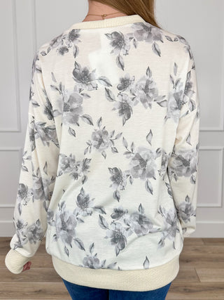 Back view of floral knit long-sleeve top, off-white with grey floral print and ribbed hem