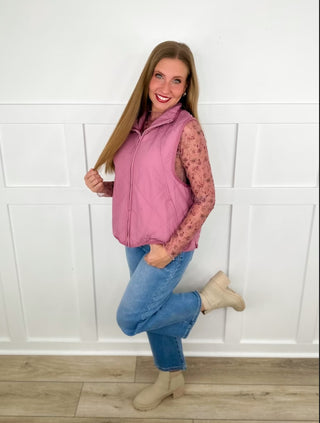 Pink sleeveless vest over lace sleeves, blue jeans, tan ankle boots.