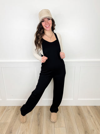 Cream cardigan over black sleeveless jumpsuit with matching knit beanie