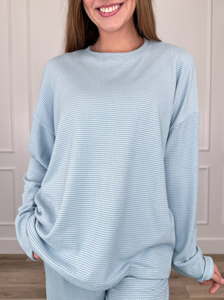 Light blue long-sleeve crewneck top with waffle-knit texture, relaxed fit