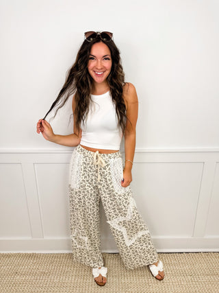 White sleeveless crop top with cream patterned wide-leg pants and tan sandals