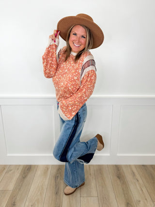 Floral long-sleeve top and blue jeans with tan wide-brim hat