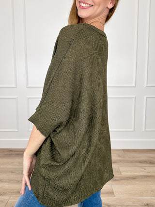 Olive green knit poncho top, three-quarter sleeve style with loose drape