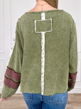 Green long-sleeve top, back vent with rectangular patch and burgundy floral trim