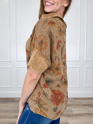 Brown short-sleeve knit top with floral print and buttoned collar, side view