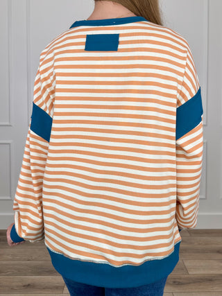 Striped knit long-sleeve top, back view, orange/white stripes with teal accents