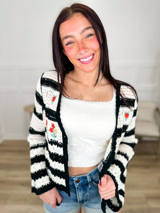 Cream knit long-sleeve cardigan with black stripes, red floral motifs, button front