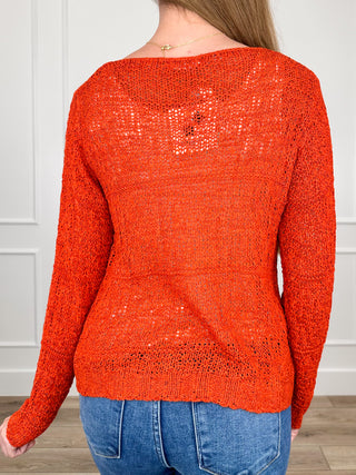 Orange knit long-sleeve top with all-over sparkle, round neckline