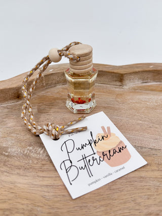 Golden glass scent diffuser bottle with cork cap and braided cord, labeled “Pumpkin Buttercream”.