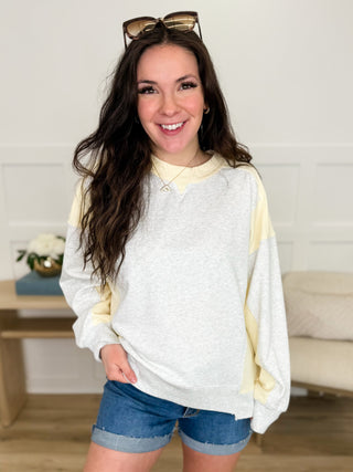 Long-sleeve cotton top with crew neck, cream front and yellow cuffed sleeves.
