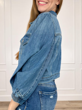 Medium-wash cropped denim jacket side profile, buttoned chest pockets, 3/4 sleeves