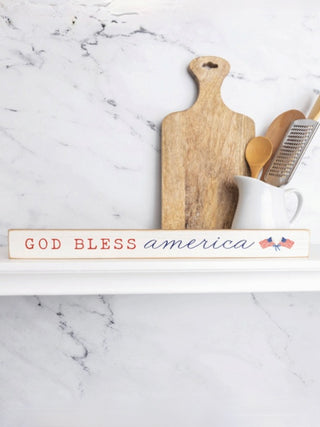 Wooden wall sign with “God Bless America” text and small patriotic icons