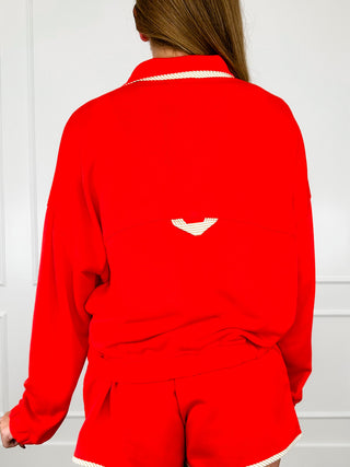 Red long-sleeve pullover top, back view with small logo patch and gathered waist