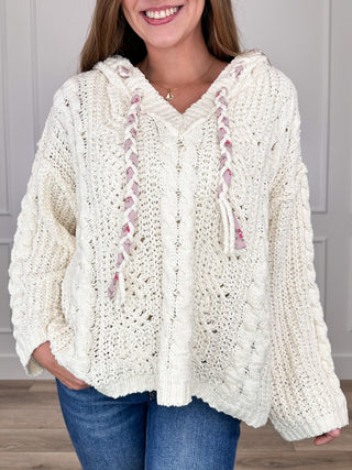 Ivory knit hooded long-sleeve sweater with textured cable stitch and tassel details