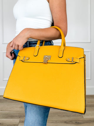 Yellow faux leather handbag with top handles and gold-tone front clasp hardware