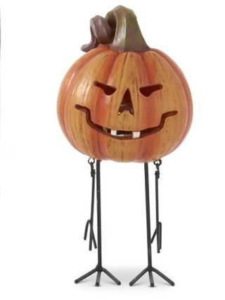 Resin jack-o'-lantern decor with carved grin face, close view on black tripod legs