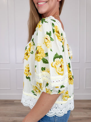 Cream cotton short sleeve top with yellow rose print and white lace hem, side view