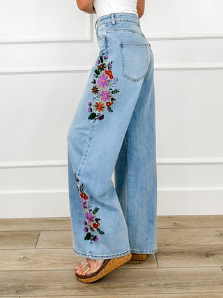 Light wash high-rise wide-leg jeans with floral embroidery on back leg, side view