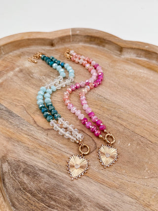 Beaded necklace with teal, light blue, and pink beads and gold sunburst charms