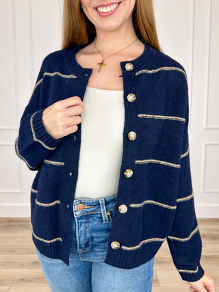 Navy blue knit button-up cardigan with long sleeves and cream striped front pockets