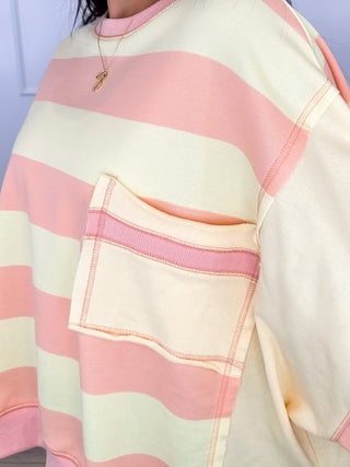 Pastel striped pullover sweatshirt with ribbed trim and front pocket detail.