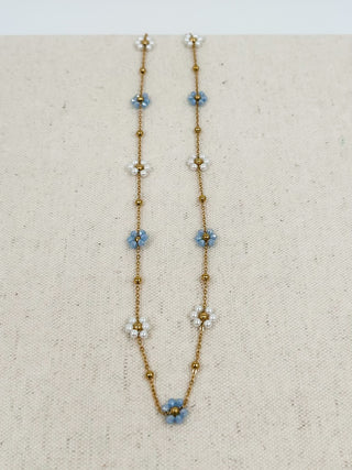 Gold beaded necklace with dangling blue flower charms and small pearl accents