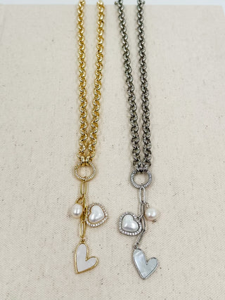 Heart pendant necklace set on display with gold and silver peace charms and pearls