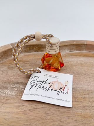 Amber-red glass scent diffuser bottle with cork cap and braided cord, labeled “Pumpkin Marshmallow”.