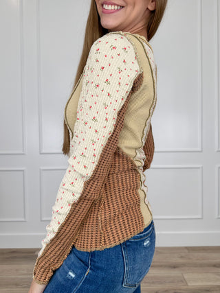 Long-sleeve cream top with red sprig print and tan side panels, rounded crew neck