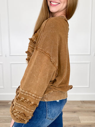 Brown long-sleeve cotton top with ruched sleeve cuffs and layered chest ruffle trim