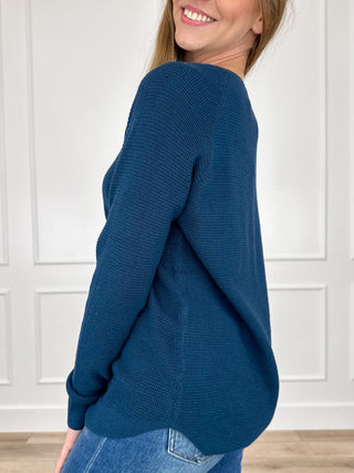 Blue knit long-sleeve sweater top, side view with rounded hem and crew neck