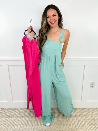 Mint green sleeveless jumpsuit with square neckline; holding a hot pink spare.