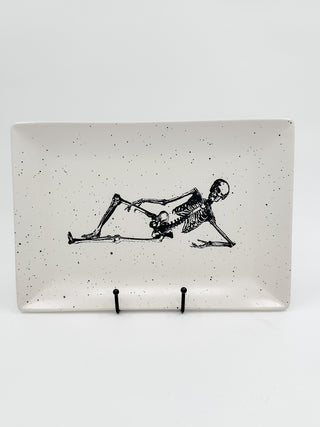 White ceramic tray with black skeleton illustration and two display pegs at bottom
