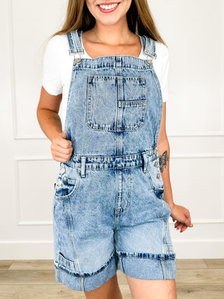 Medium wash denim bermuda overall shorts with square bib and front patch pockets