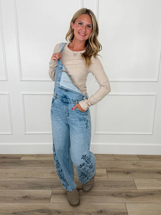 Medium wash denim barrel-leg overalls with embroidered details, adjustable straps and bib front