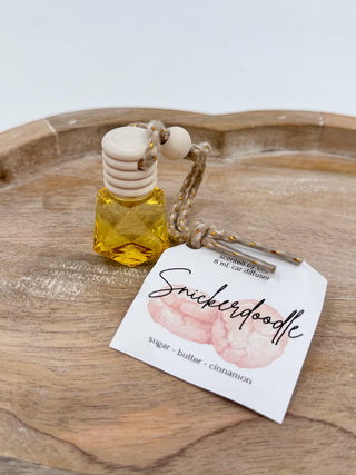 Yellow glass scent diffuser bottle with cork cap and braided cord, labeled “Snickerdoodle”.