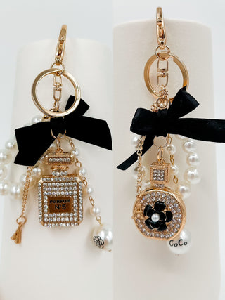 Gold keychain pair: perfume-bottle charm and round CoCo charm, both with black ribbon