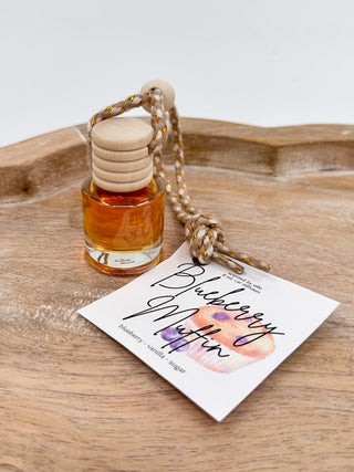 Amber glass scent diffuser bottle with cork cap and braided cord, labeled “Blueberry Muffin”.