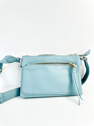 Faux leather crossbody handbag in light blue with zip-top, front pocket, and strap