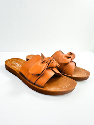 Faux leather slide sandals with orange bow detail, cushioned footbed